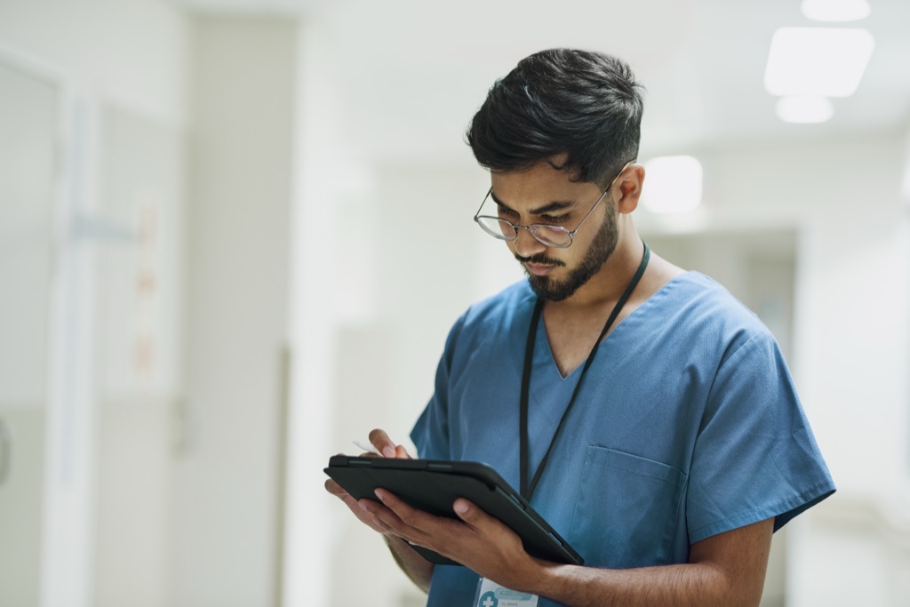 A healthcare worker reviewing a tablet in a hospital corridor