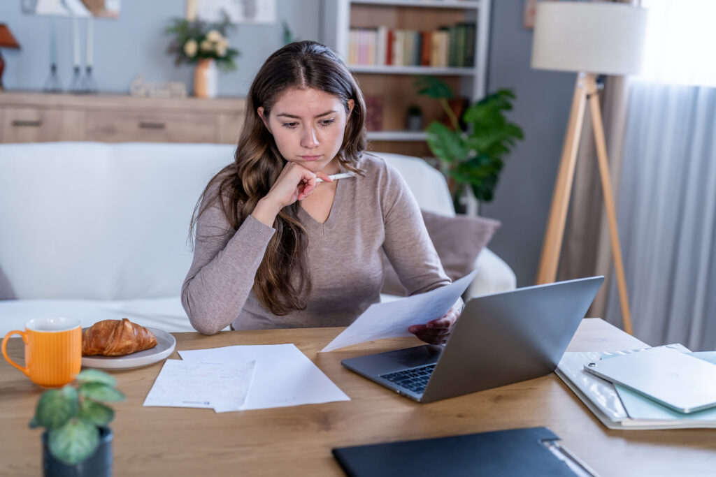 A borrower at a kitchen table reading an official letter about their student loans.