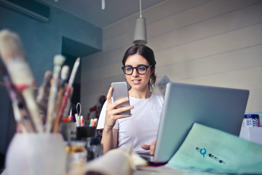 A mid-career professional working at a home-office desk with a laptop and paperwork, reviewing federal student loan repayment options under the Repayment Assistance Plan.