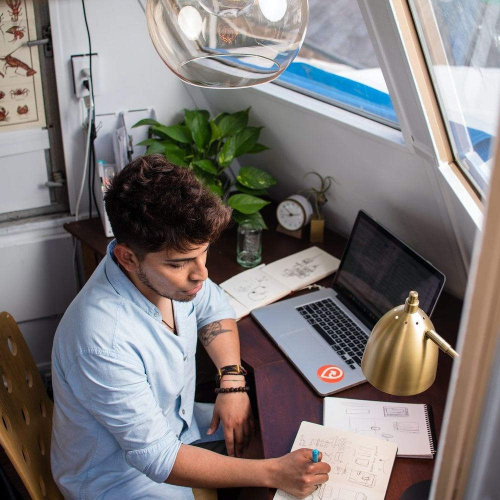 A borrower at a home desk reviewing a student loan servicer notice beside a laptop.