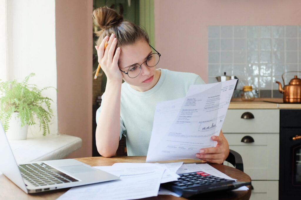 A borrower at a kitchen table reading a loan statement beside an open laptop, working out whether a late payment still counts toward PSLF.